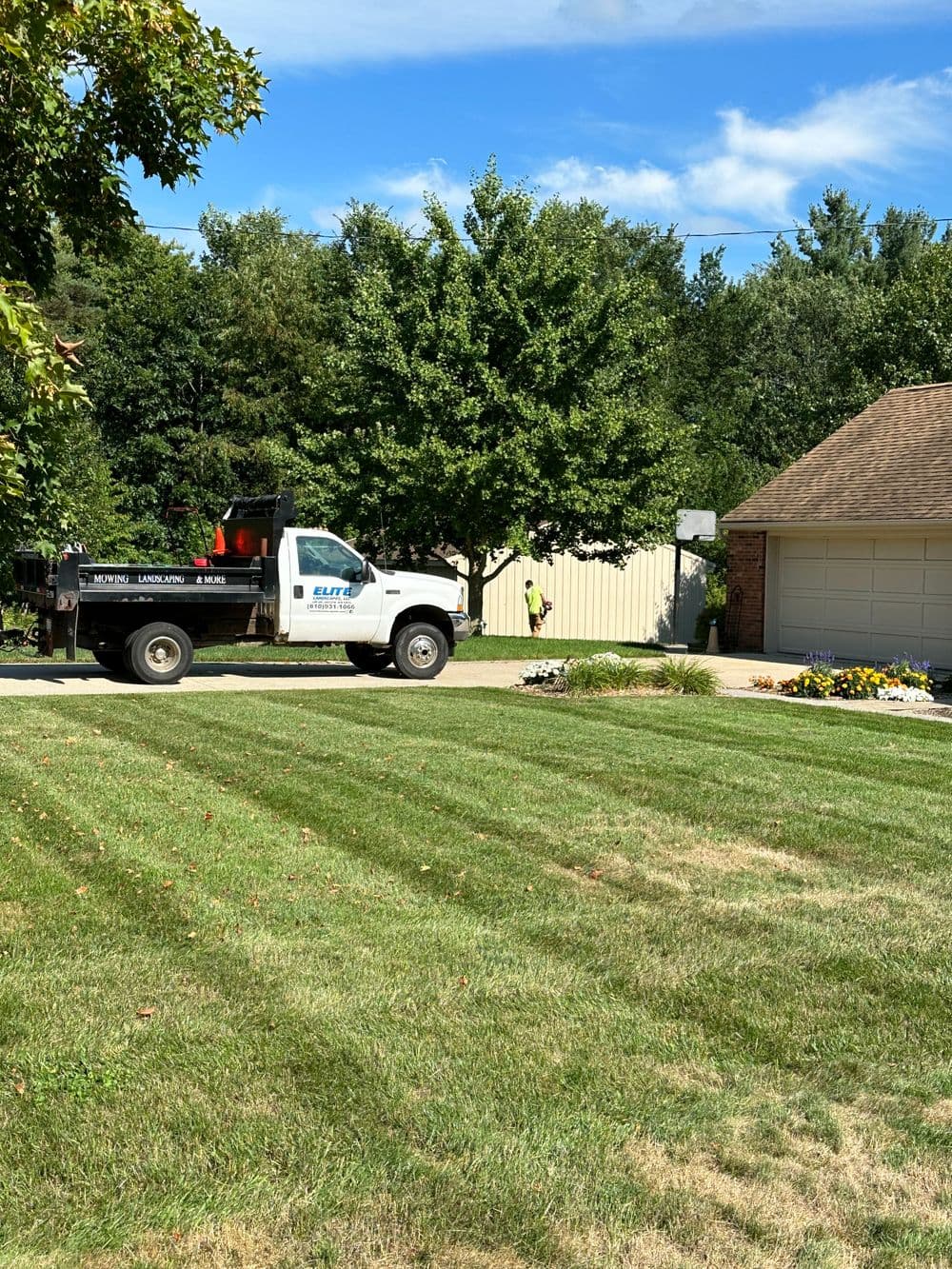 Elite landscaping truck in residential area with manicured lawn and trees.
