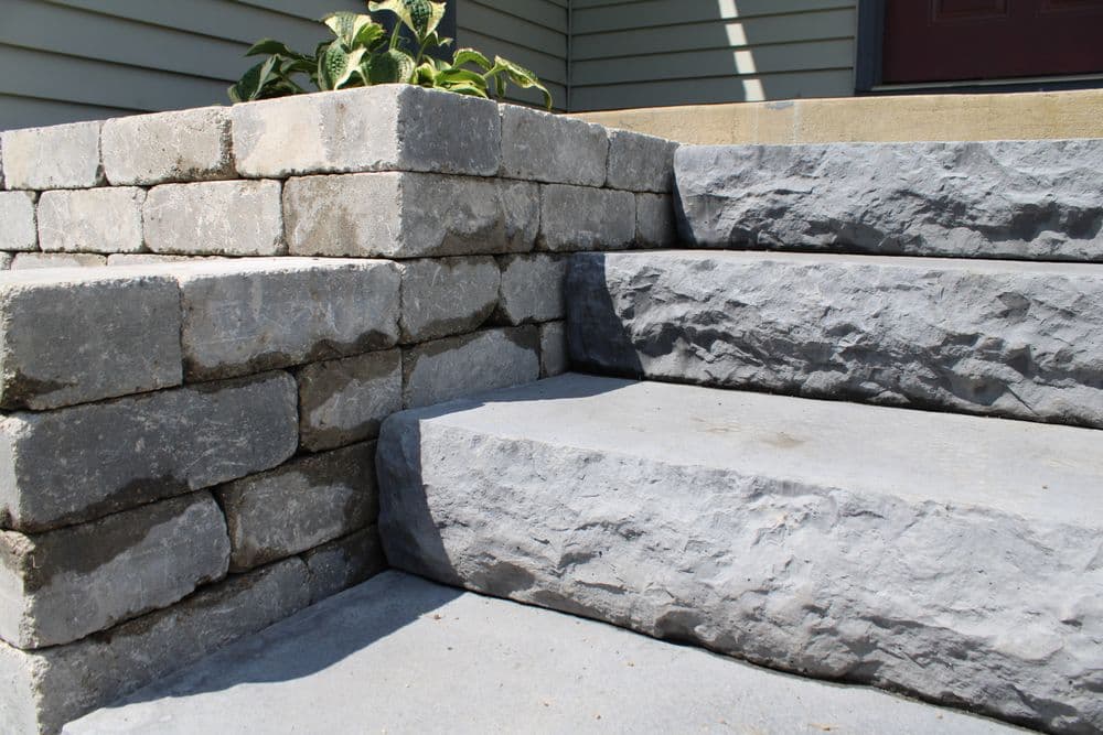 Stone steps with raised planters, showcasing textured gray blocks and concrete transitions.