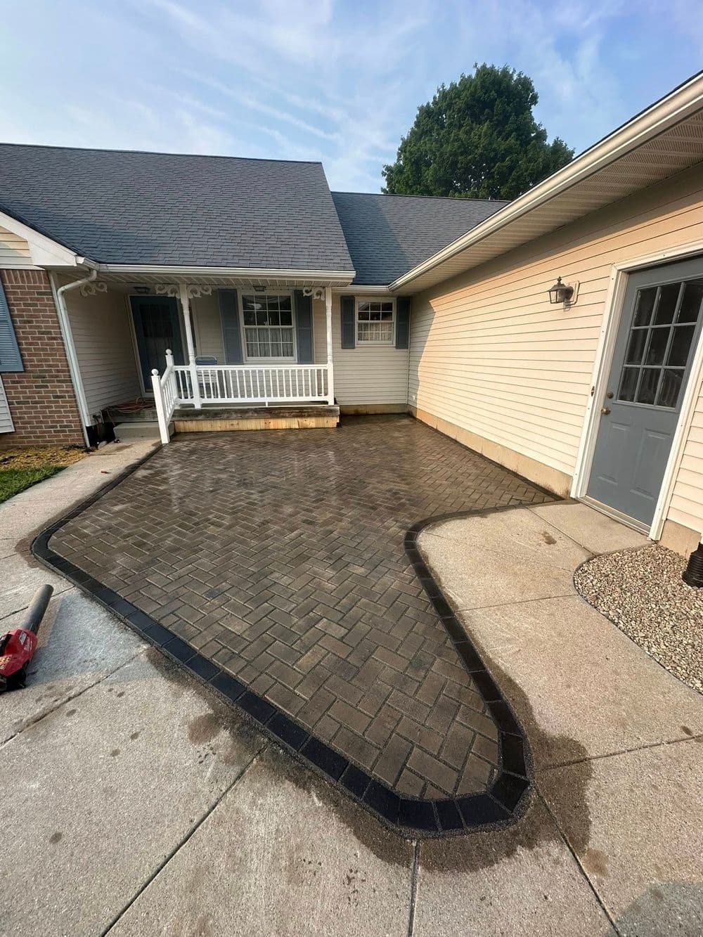 Paved driveway with curved border, newly installed next to residential home exterior.
