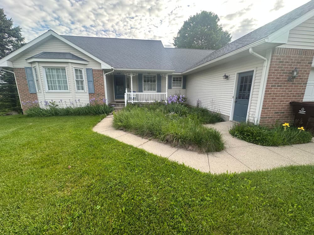 Charming single-story home with landscaped front yard and flower garden under a cloudy sky.