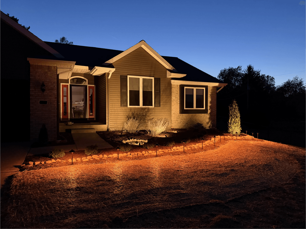 Modern home exterior at dusk with warm lighting and landscaped garden.
