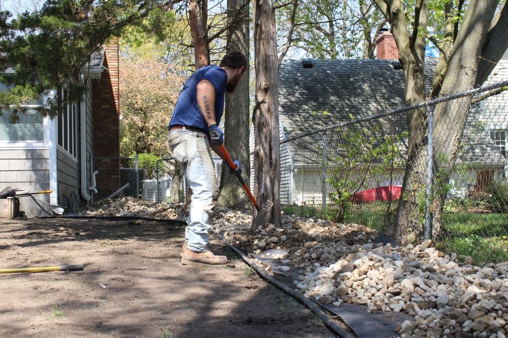 Paved driveway with curved border, newly installed next to residential home exterior.